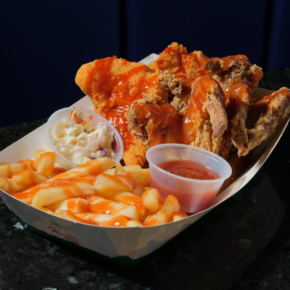 Harold's Chicken KSU fried chicken meal with fries, coleslaw, and hot sauce in a paper tray.