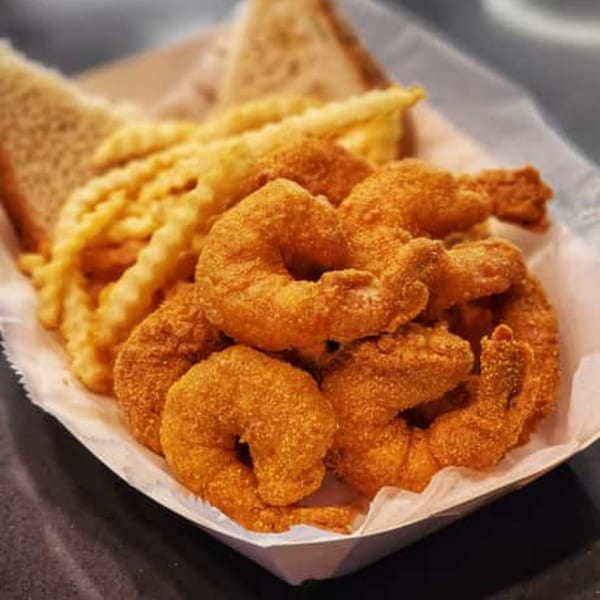 A serving of crispy fried shrimp, crinkle-cut fries, and toast in a paper tray.