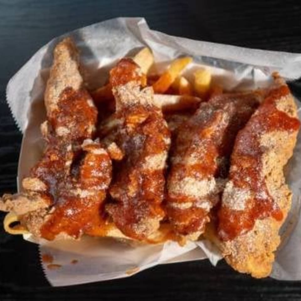 Harolds Chicken KSU fried chicken strips and fries, drizzled with sauce and seasoning in a basket.