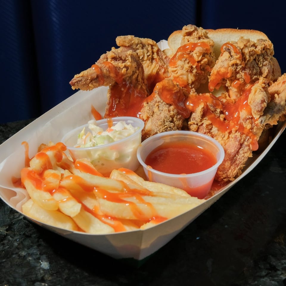 Harold's Chicken KSU fried chicken meal with fries, coleslaw, and hot sauce in a paper tray.